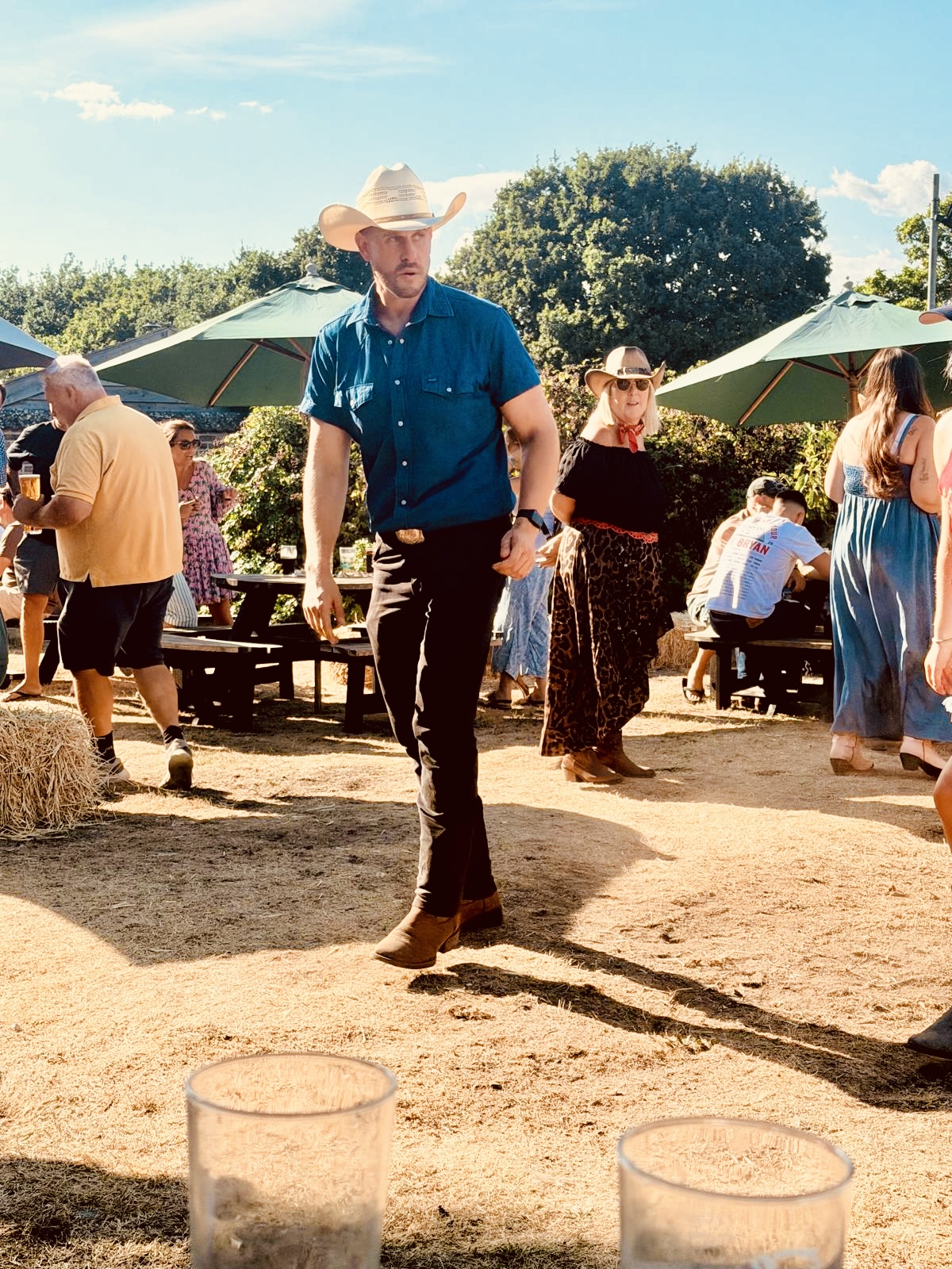 Dan Waterman in a cowboy hat line dancing at an outdoor summer event